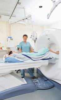 Full length portrait of female nurse with patient in CT scan room