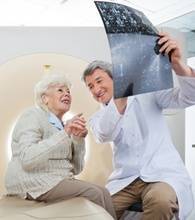 Mature male radiologist with an elderly female patient looking at CT scan results